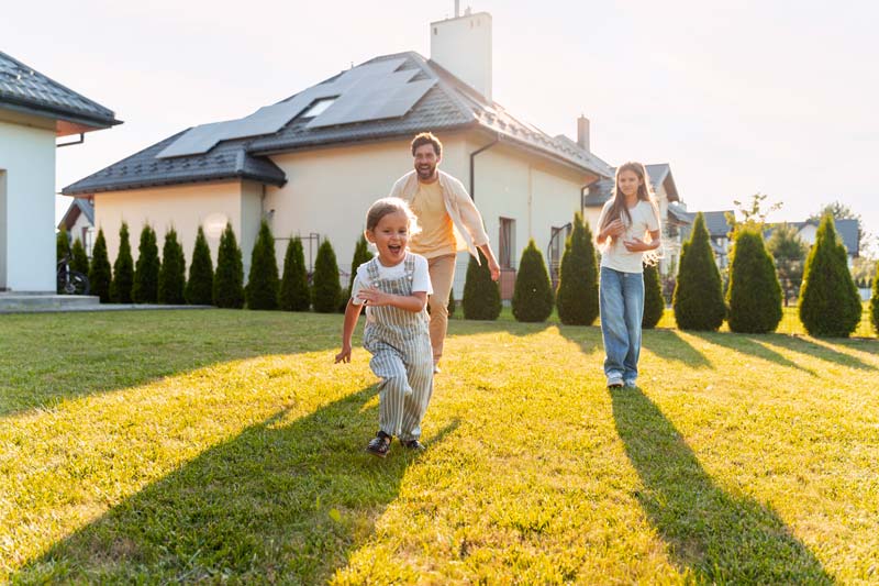 Family enjoying the outdoors in front of a home with solar panels