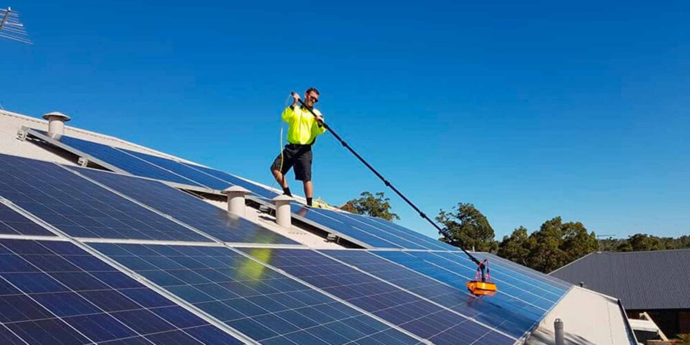 Green Sun Solutions team member cleaning solar panels on a roof